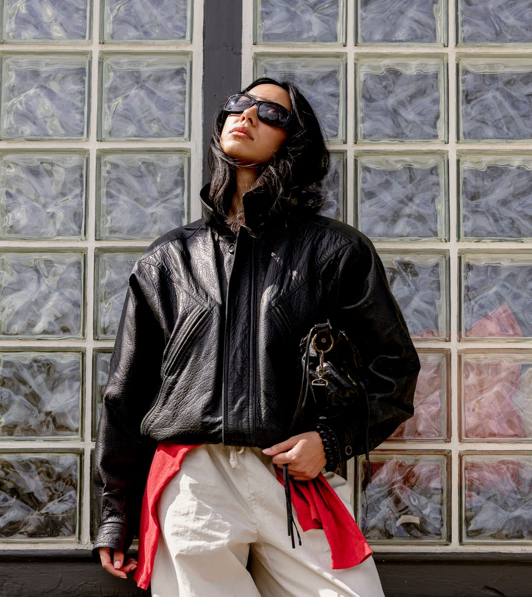 Model in a leather jacket standing in front of a glass-block wall