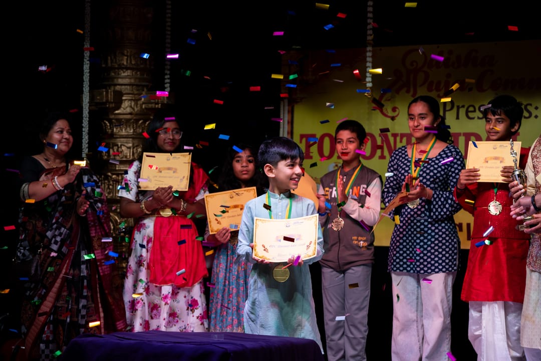 Children holding certificates on stage beneath colorful banners