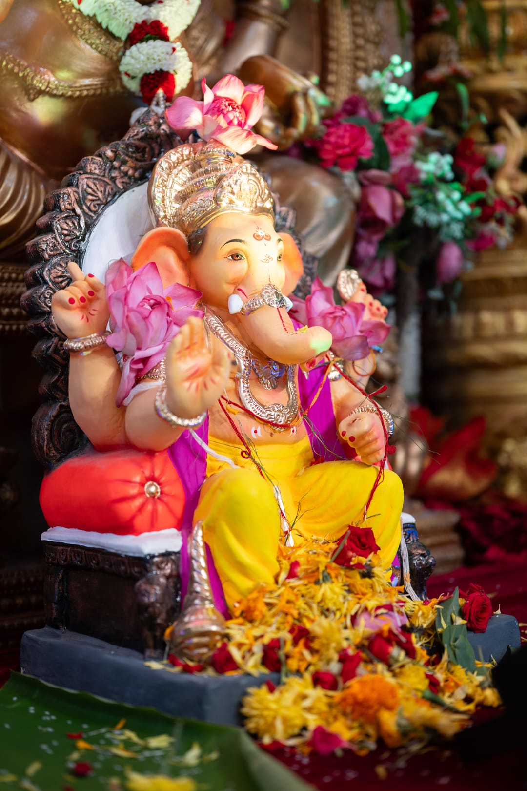 Painted Ganesha idol decorated with pink flowers and marigolds