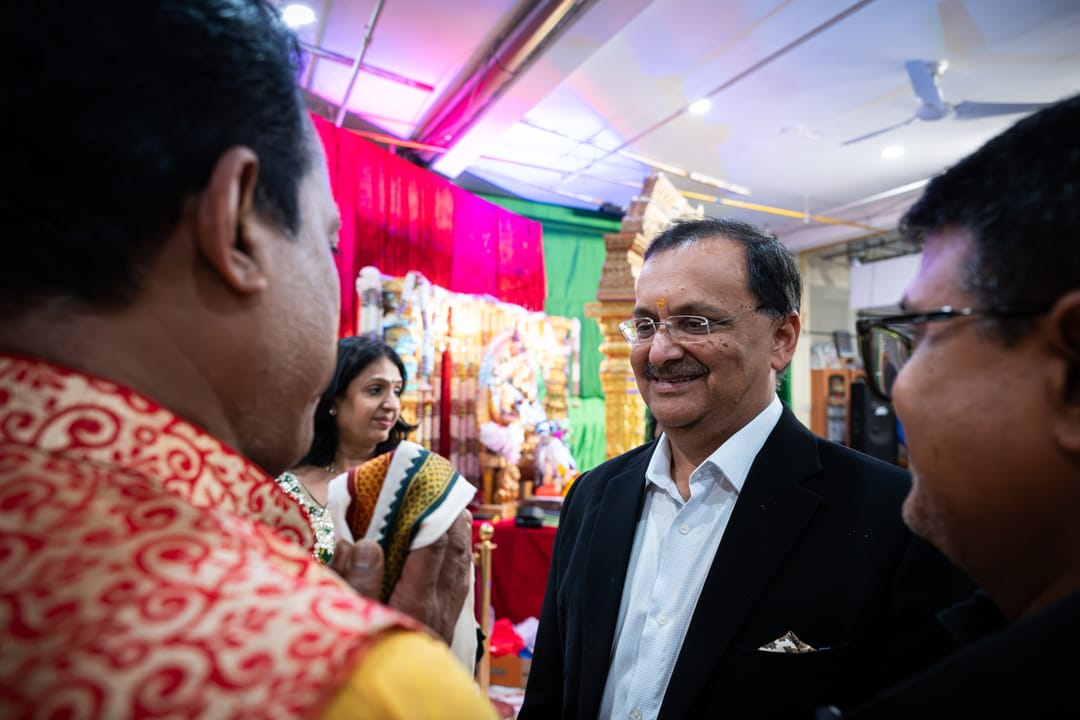 Guests greeting one another at a celebration beneath colorful lights