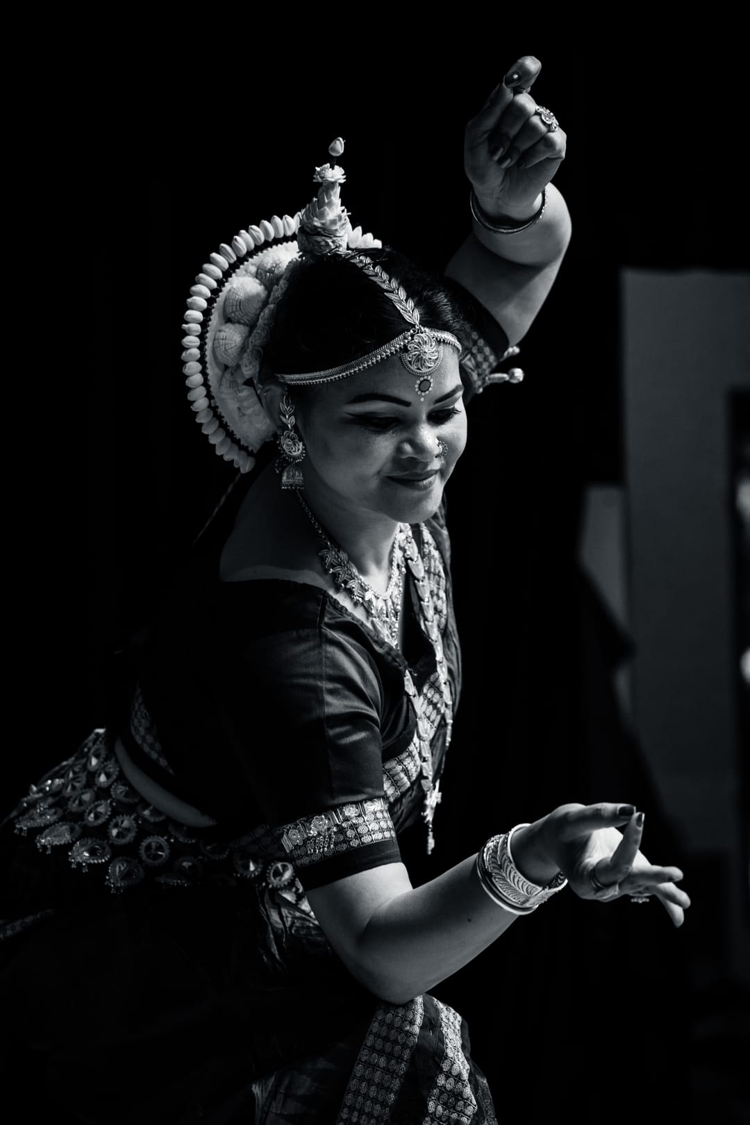 Black and white portrait of a classical dancer in mid-gesture, in ornate jewelry and headdress