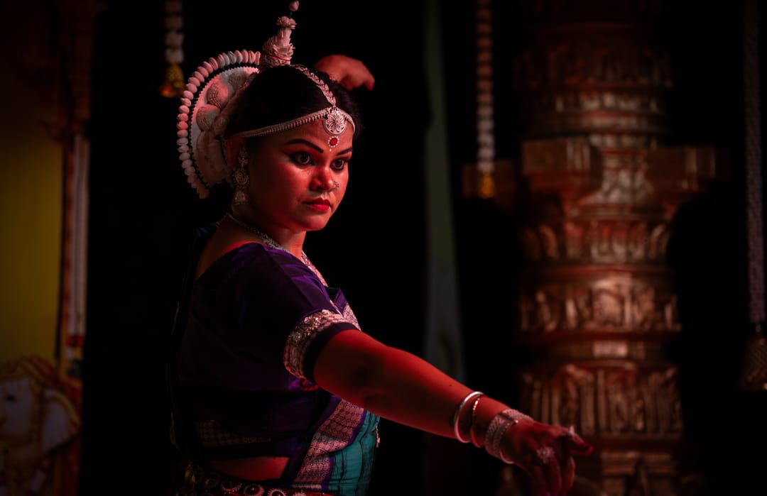 Classical dancer in a dark costume and headdress under low stage light