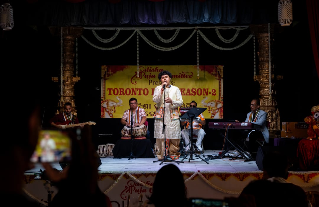 A performer on a stage beneath a yellow banner with an audience in the foreground