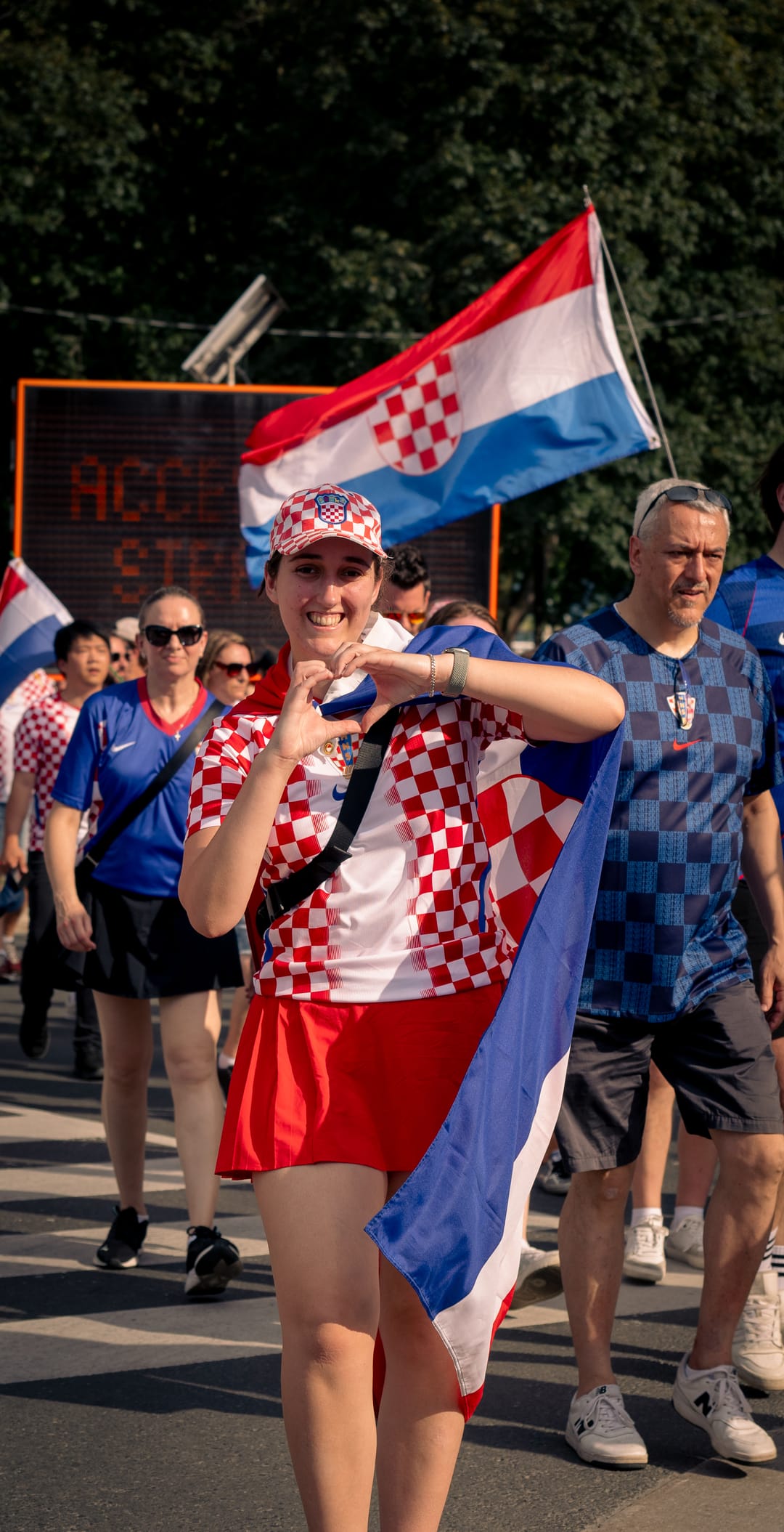 A supporter in a red and white checkered Croatia shirt waving a flag in the street