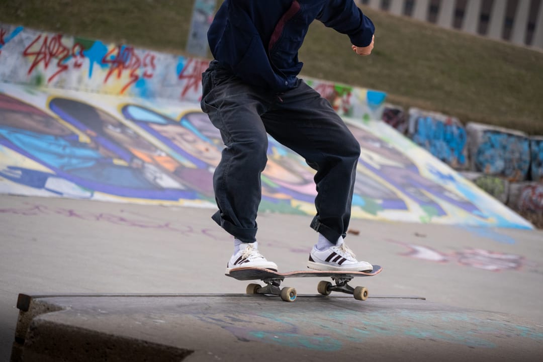 A skateboarder mid-trick on a graffiti-covered ramp